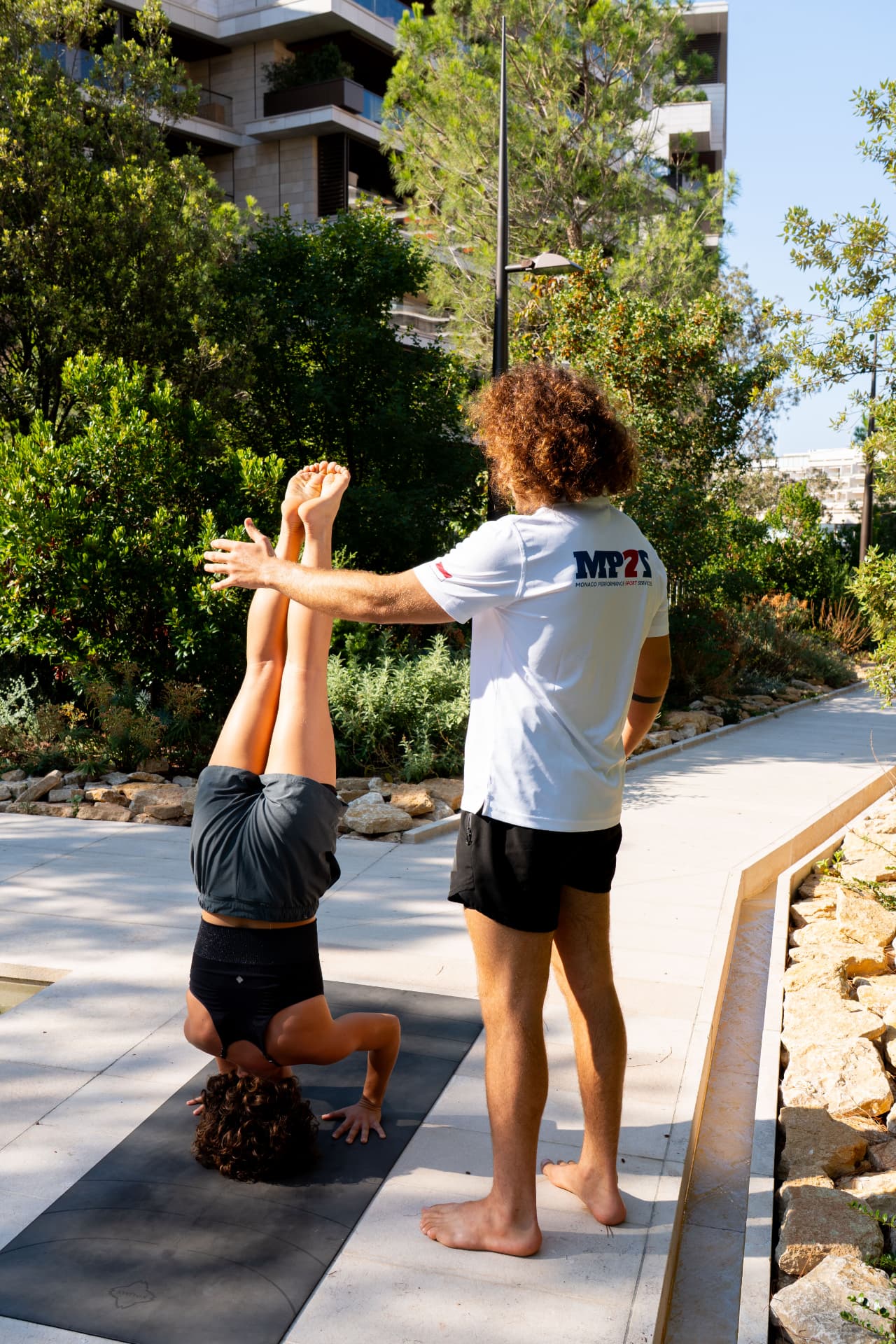 Lucas accompagne une élève en équilibre dans un parc de Monaco